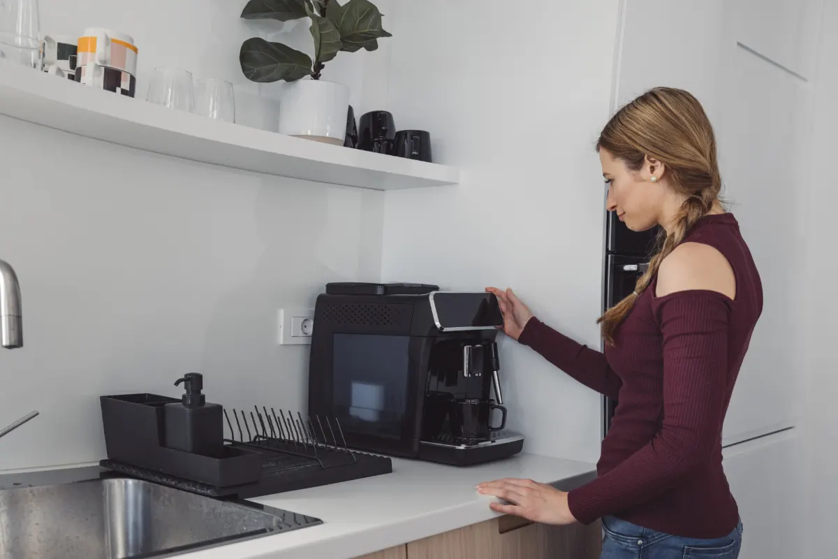 mujer usando cafetera en rincón de café en casa