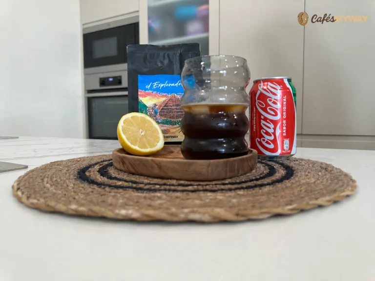 Café con Coca-Cola servido con hielo junto a un limón, una lata de cola y café El Explorador de Cafés MyWay