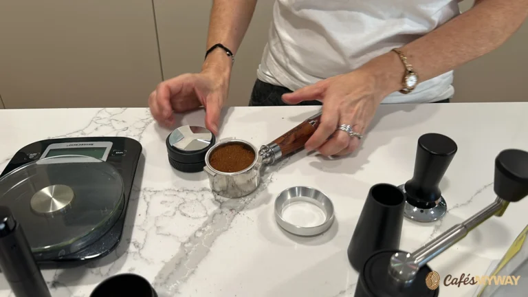 Café molido dentro de un portafiltro junto a una báscula y accesorios de preparación