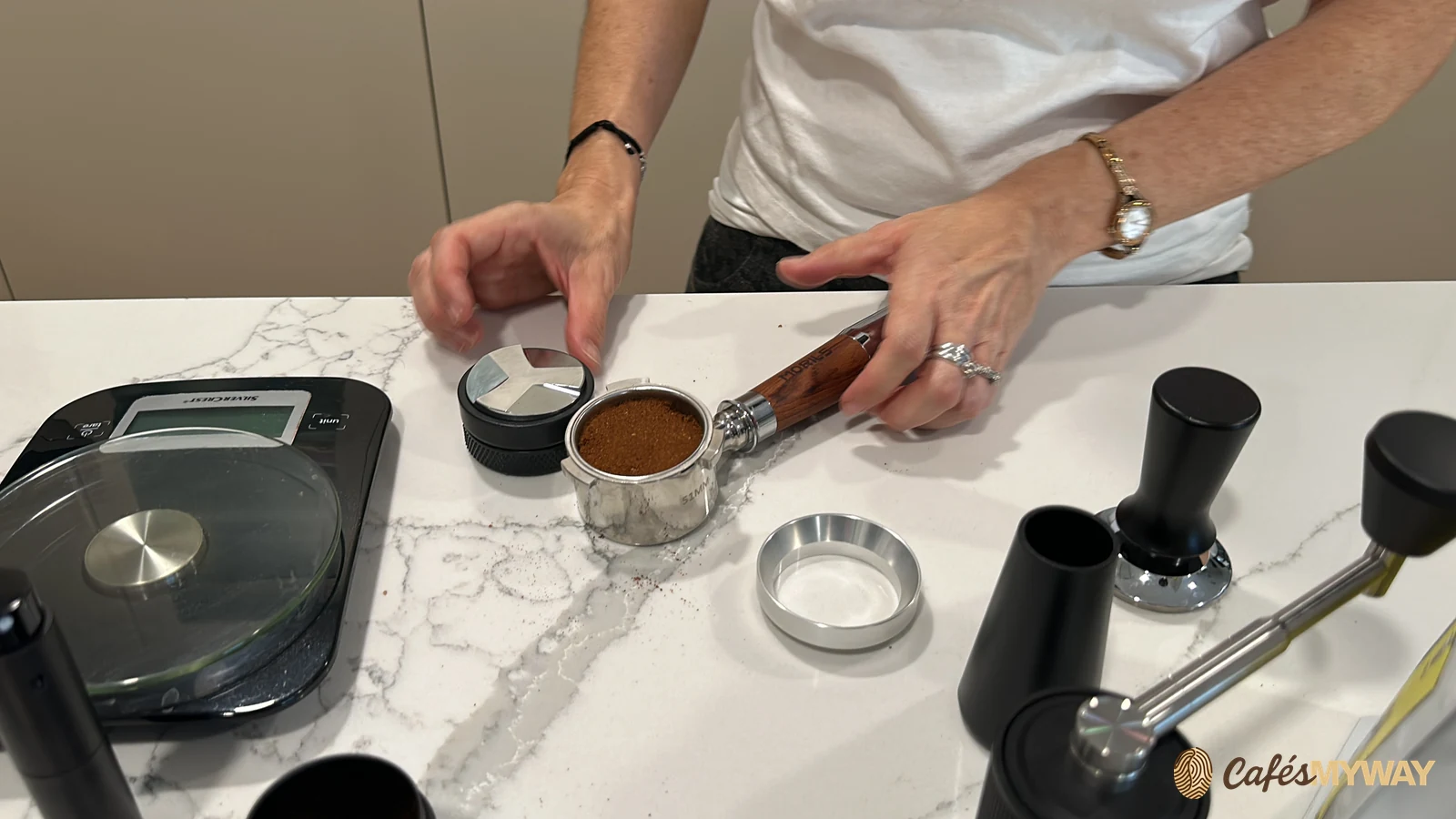 Café molido dentro de un portafiltro junto a una báscula y accesorios de preparación