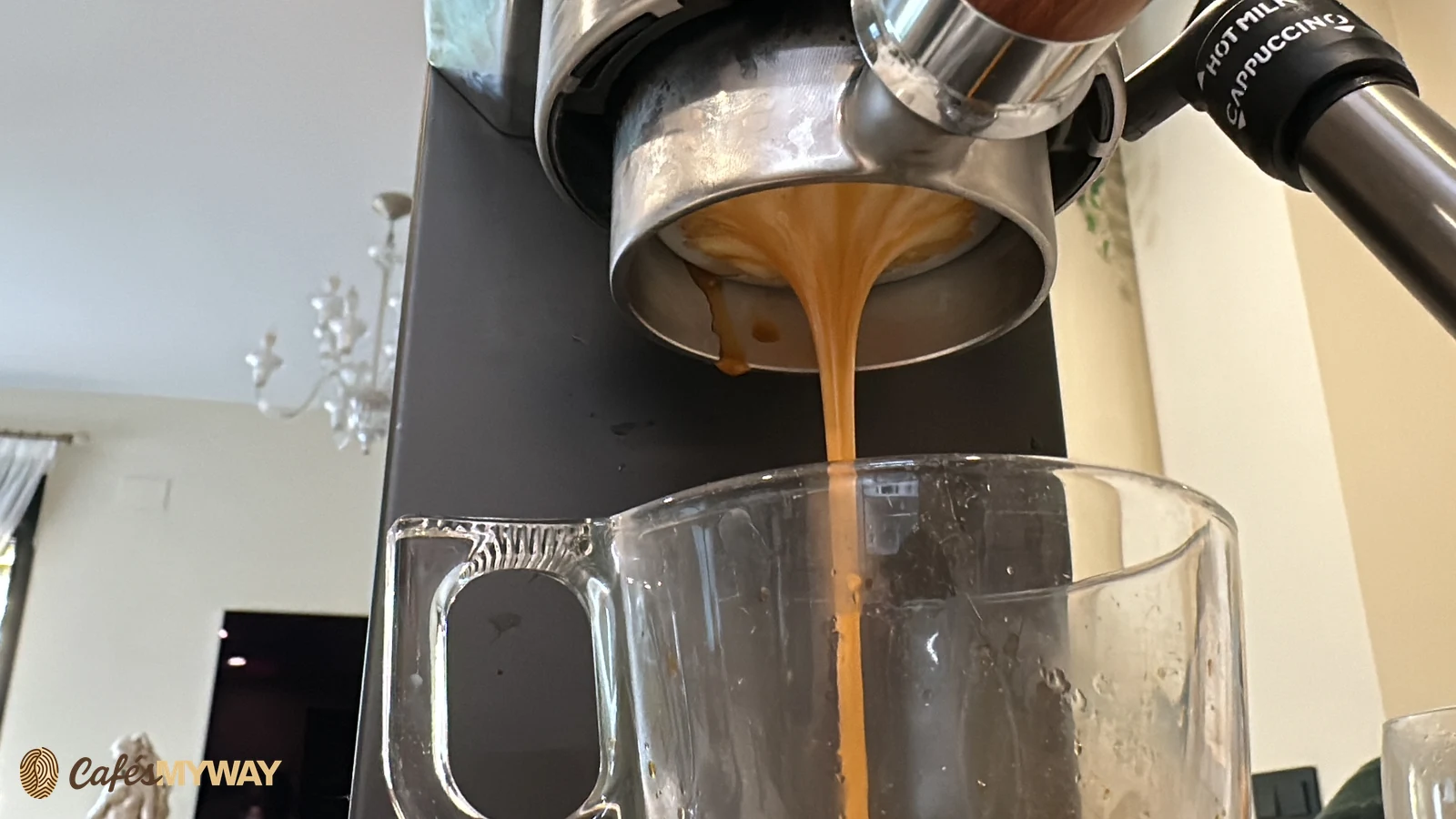 Café saliendo por la base de un portafiltro sin fondo hacia una jarra de vidrio